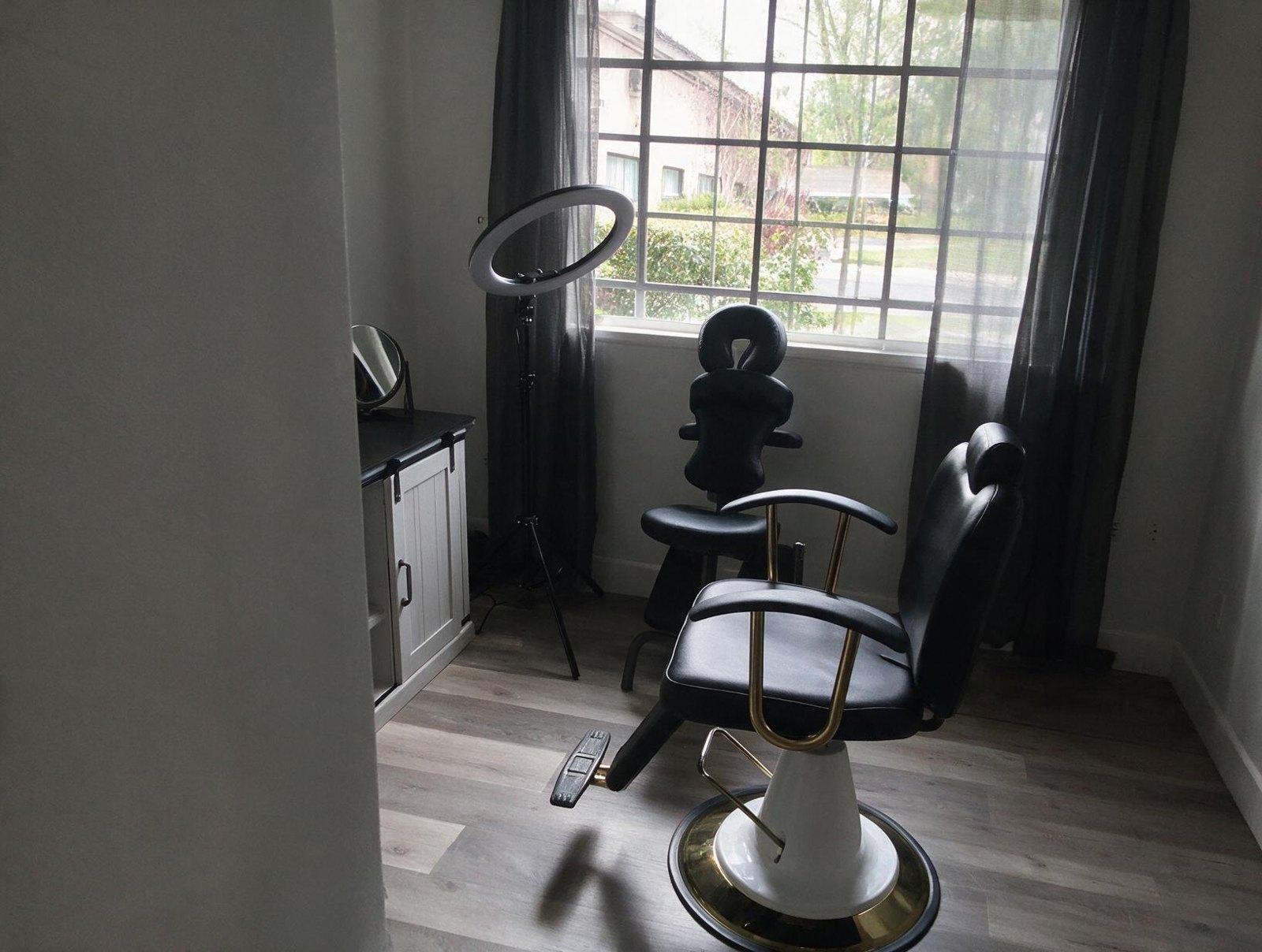 Empty treatment room with a black reclining chair, a massage-style face-rest chair